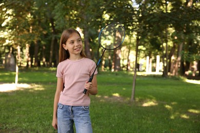 Photo of Smiling little girl with badminton racket in park