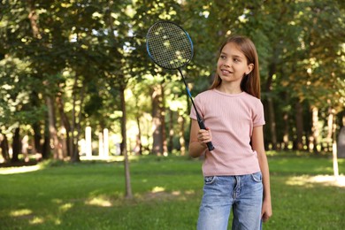 Photo of Smiling little girl with badminton racket in park. Space for text