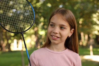 Photo of Smiling little girl with badminton racket in park