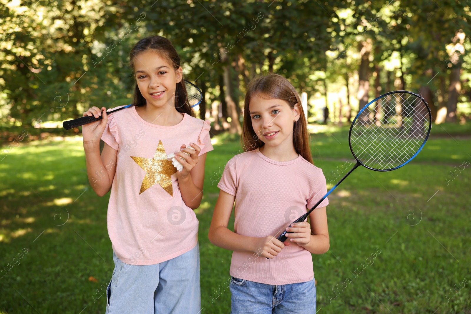 Portrait of smiling little girls with badminton rackets and shuttlecock in park Photo of Portrait of smiling little girls with badminton rackets and shuttlecock in park