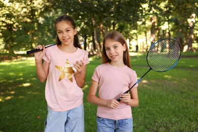 Photo of Portrait of smiling little girls with badminton rackets and shuttlecock in park