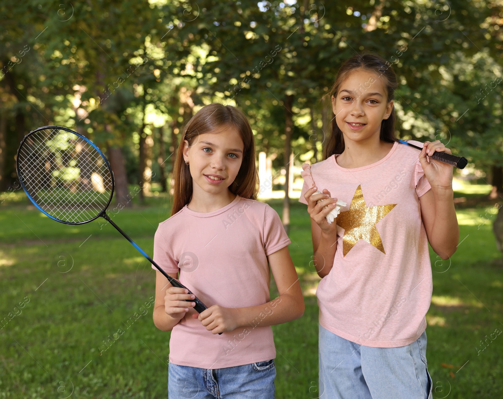 Portrait of smiling little girls with badminton rackets and shuttlecock in park Photo of Portrait of smiling little girls with badminton rackets and shuttlecock in park