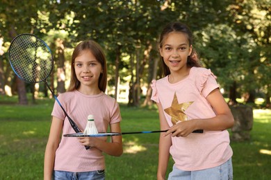 Photo of Portrait of smiling little girls with badminton rackets and shuttlecock in park
