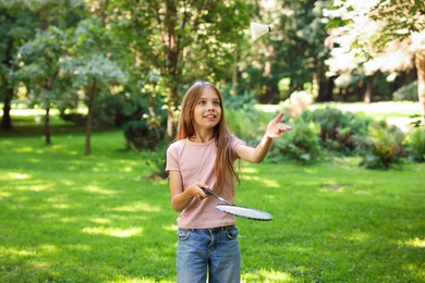 Photo of Smiling little girl playing badminton in park