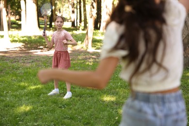 Photo of Cute little girls playing badminton in park, selective focus