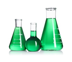 Photo of Different laboratory glassware with green liquid on mirror surface isolated on white