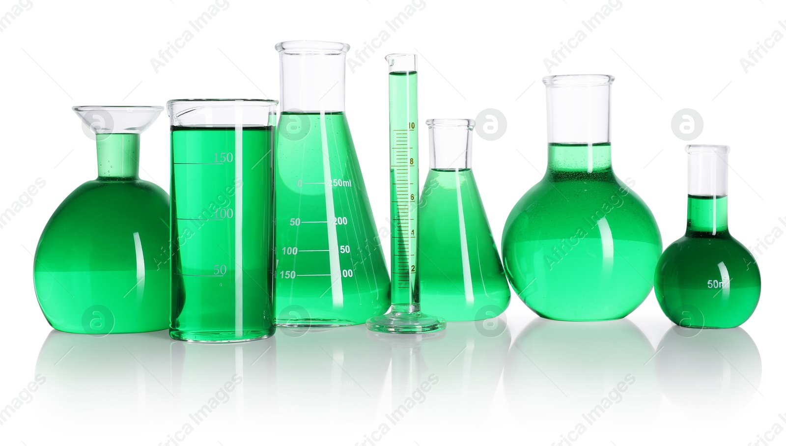 Photo of Different laboratory glassware with green liquid on mirror surface isolated on white