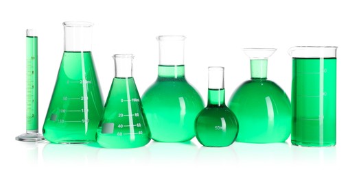 Photo of Different laboratory glassware with green liquid on mirror surface isolated on white