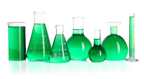 Photo of Different laboratory glassware with green liquid on mirror surface isolated on white