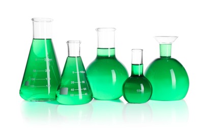 Photo of Different laboratory glassware with green liquid on mirror surface isolated on white