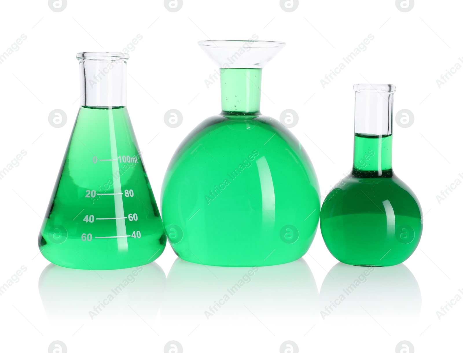 Photo of Different laboratory glassware with green liquid on mirror surface isolated on white