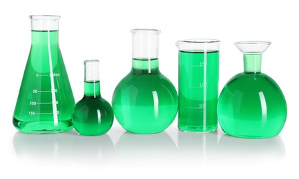 Photo of Different laboratory glassware with green liquid on mirror surface isolated on white
