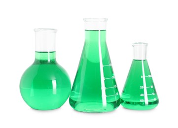 Photo of Different laboratory glassware with green liquid isolated on white