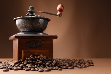 Photo of Coffee grinder and beans on brown background, closeup. Space for text