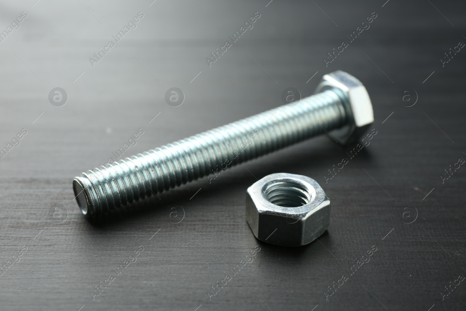 One metal bolt and hex nut on dark wooden table, closeup Photo of One metal bolt and hex nut on dark wooden table, closeup