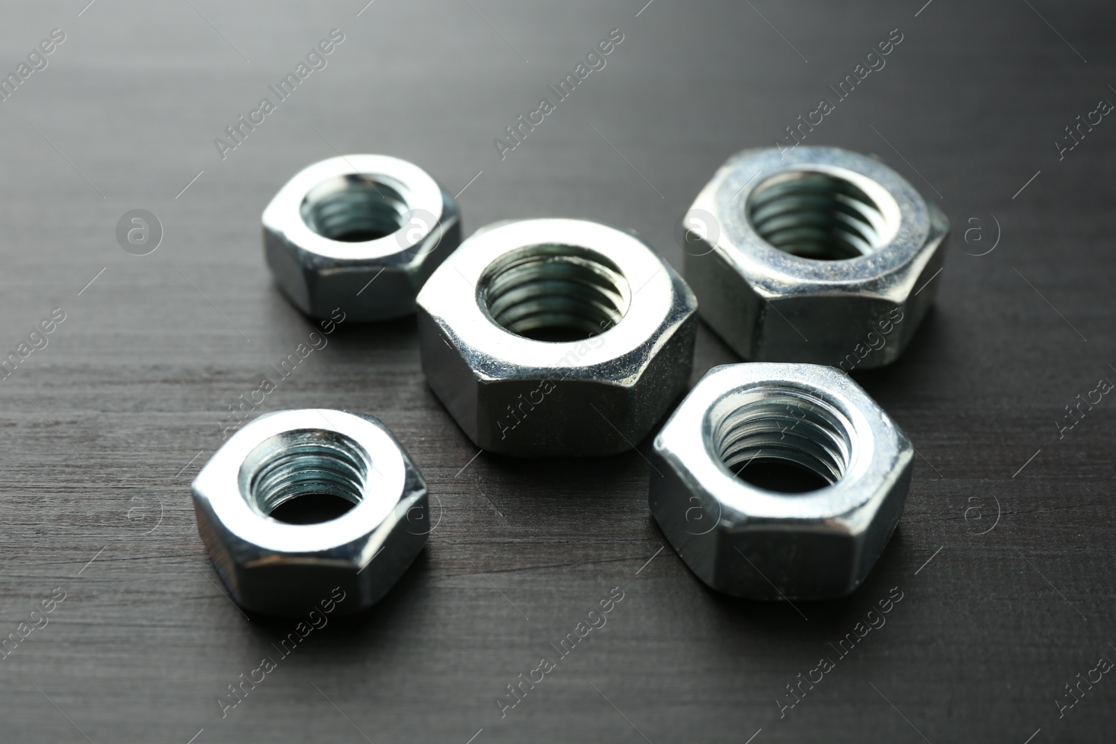 Metal hex nuts on dark wooden table, closeup Photo of Metal hex nuts on dark wooden table, closeup
