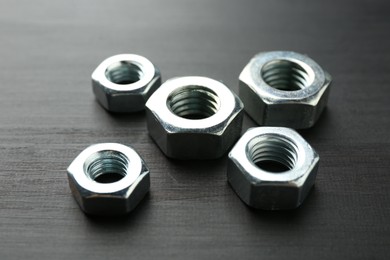 Photo of Metal hex nuts on dark wooden table, closeup