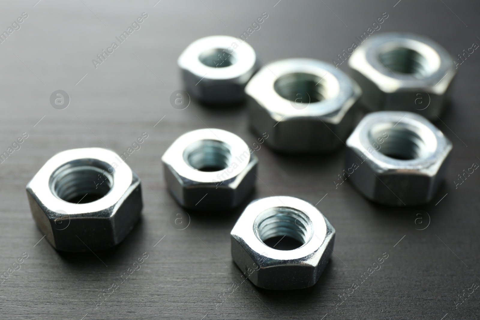 Metal hex nuts on dark wooden table, closeup Photo of Metal hex nuts on dark wooden table, closeup