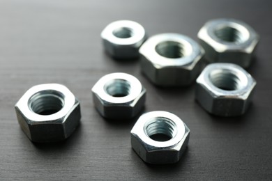 Photo of Metal hex nuts on dark wooden table, closeup