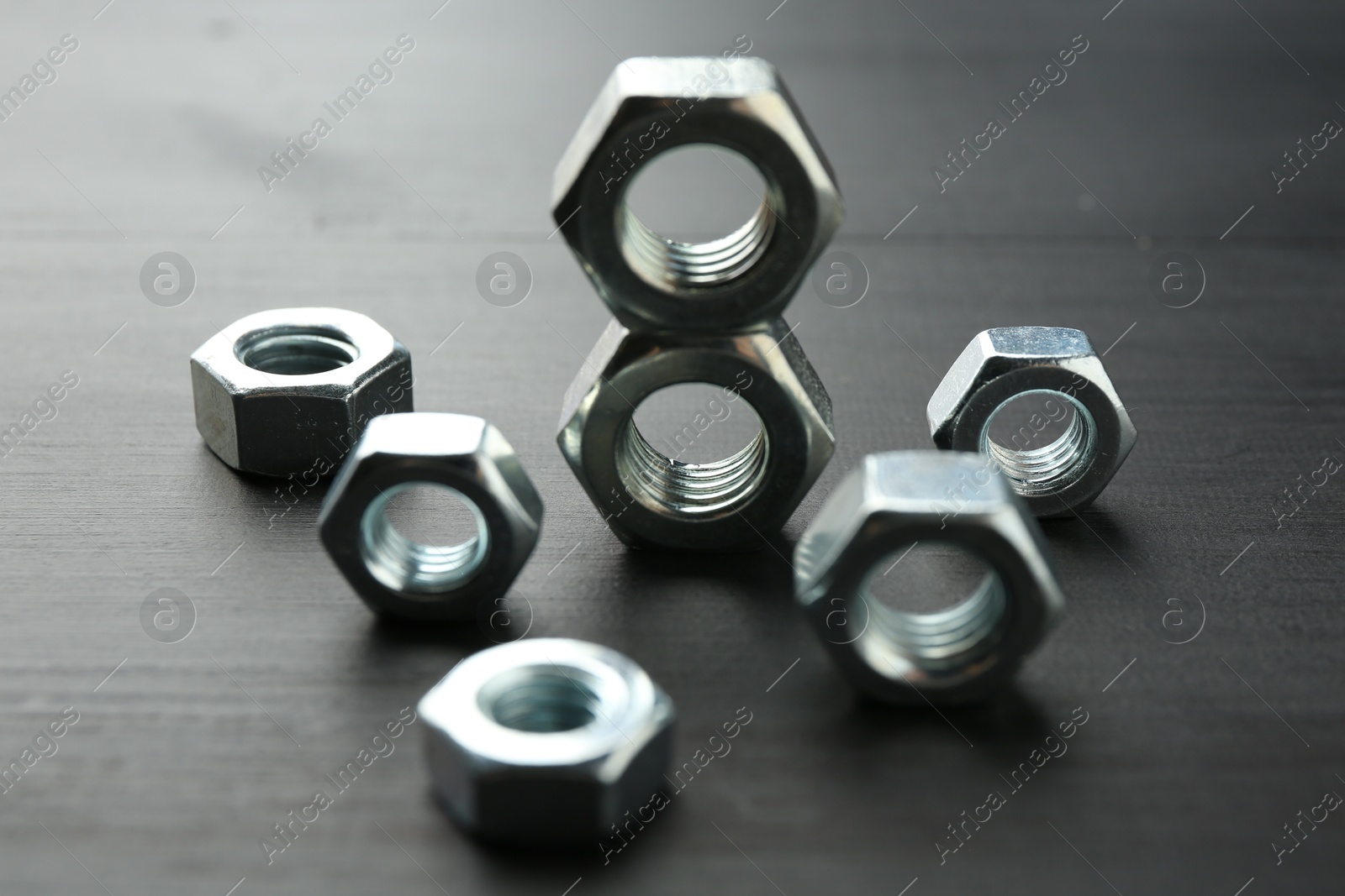 Metal hex nuts on dark wooden table, closeup Photo of Metal hex nuts on dark wooden table, closeup