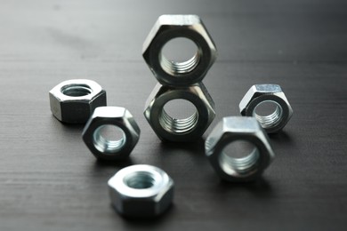 Photo of Metal hex nuts on dark wooden table, closeup