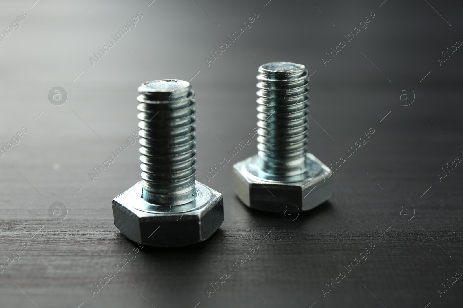 Metal bolts on dark wooden table, closeup Photo of Metal bolts on dark wooden table, closeup