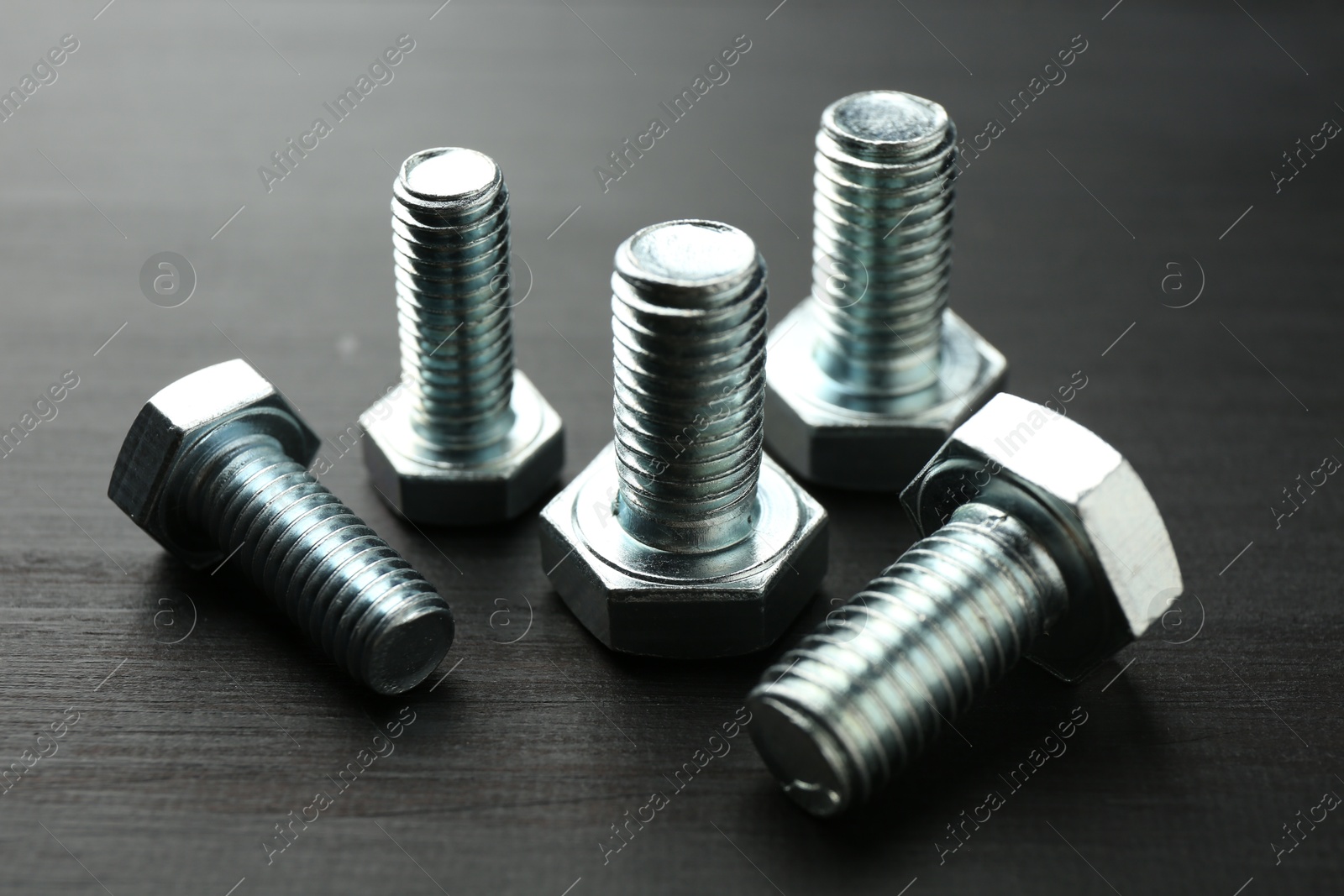 Metal bolts on dark wooden table, closeup Photo of Metal bolts on dark wooden table, closeup