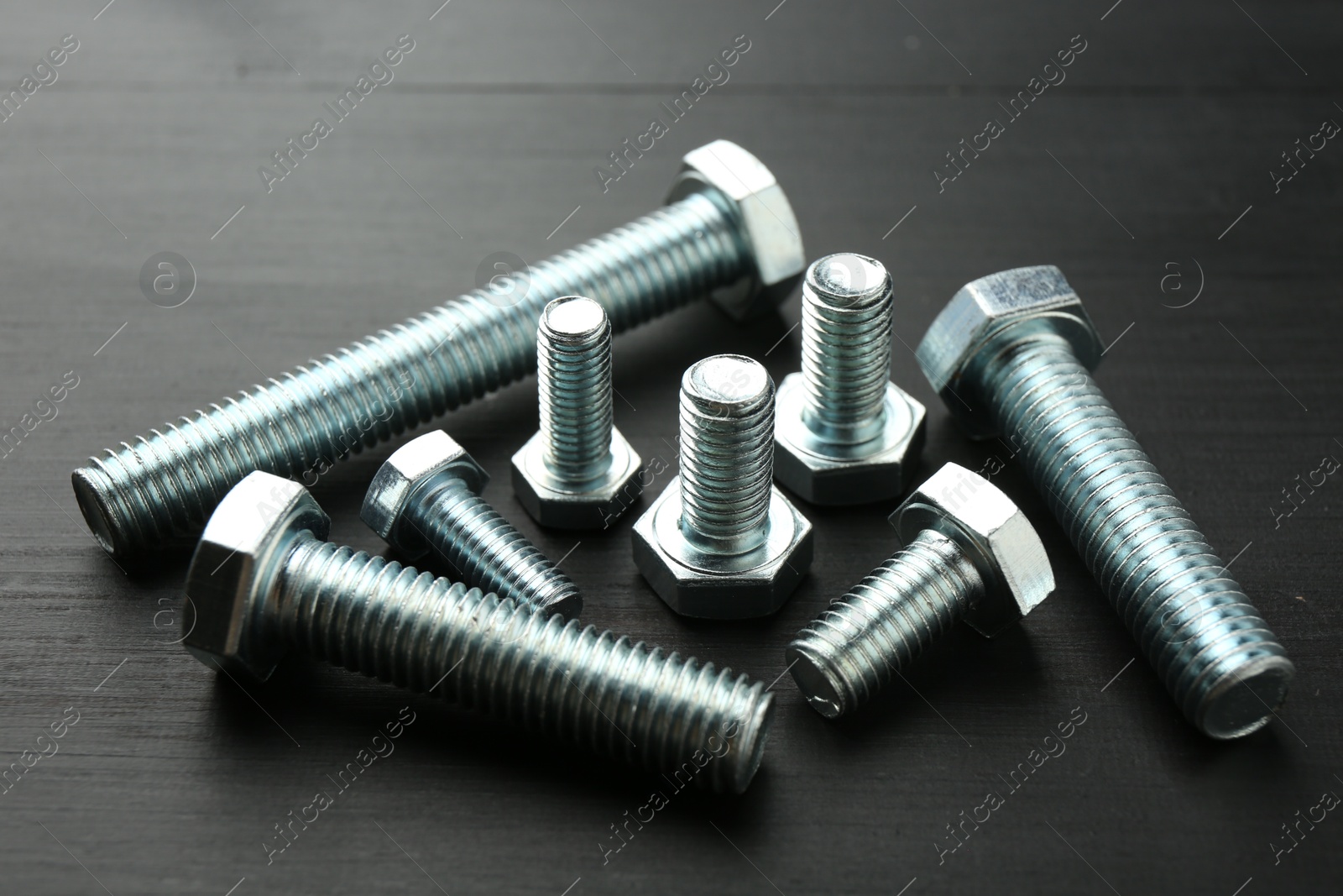 Metal bolts on dark wooden table, closeup Photo of Metal bolts on dark wooden table, closeup