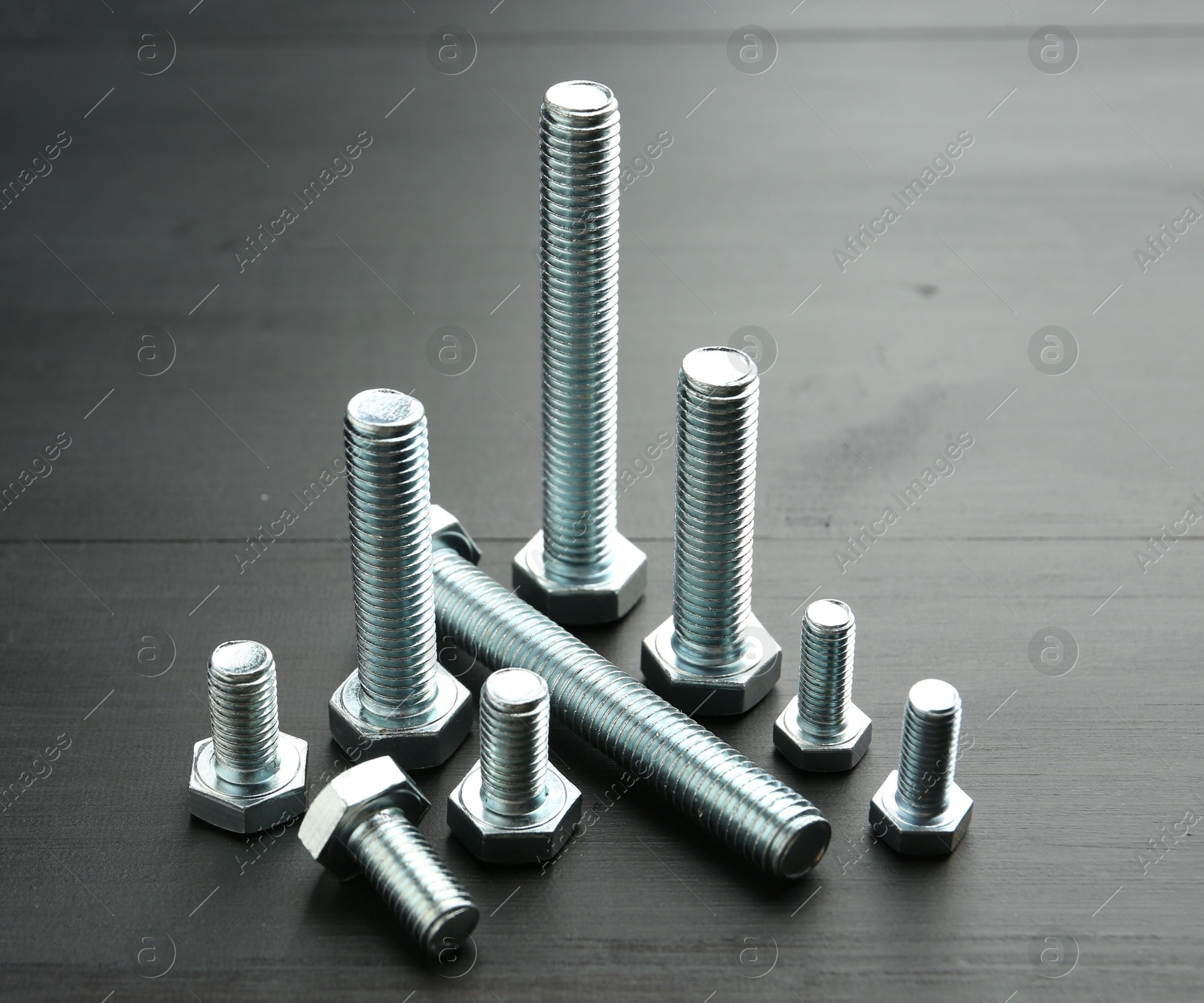 Metal bolts on dark wooden table, closeup Photo of Metal bolts on dark wooden table, closeup