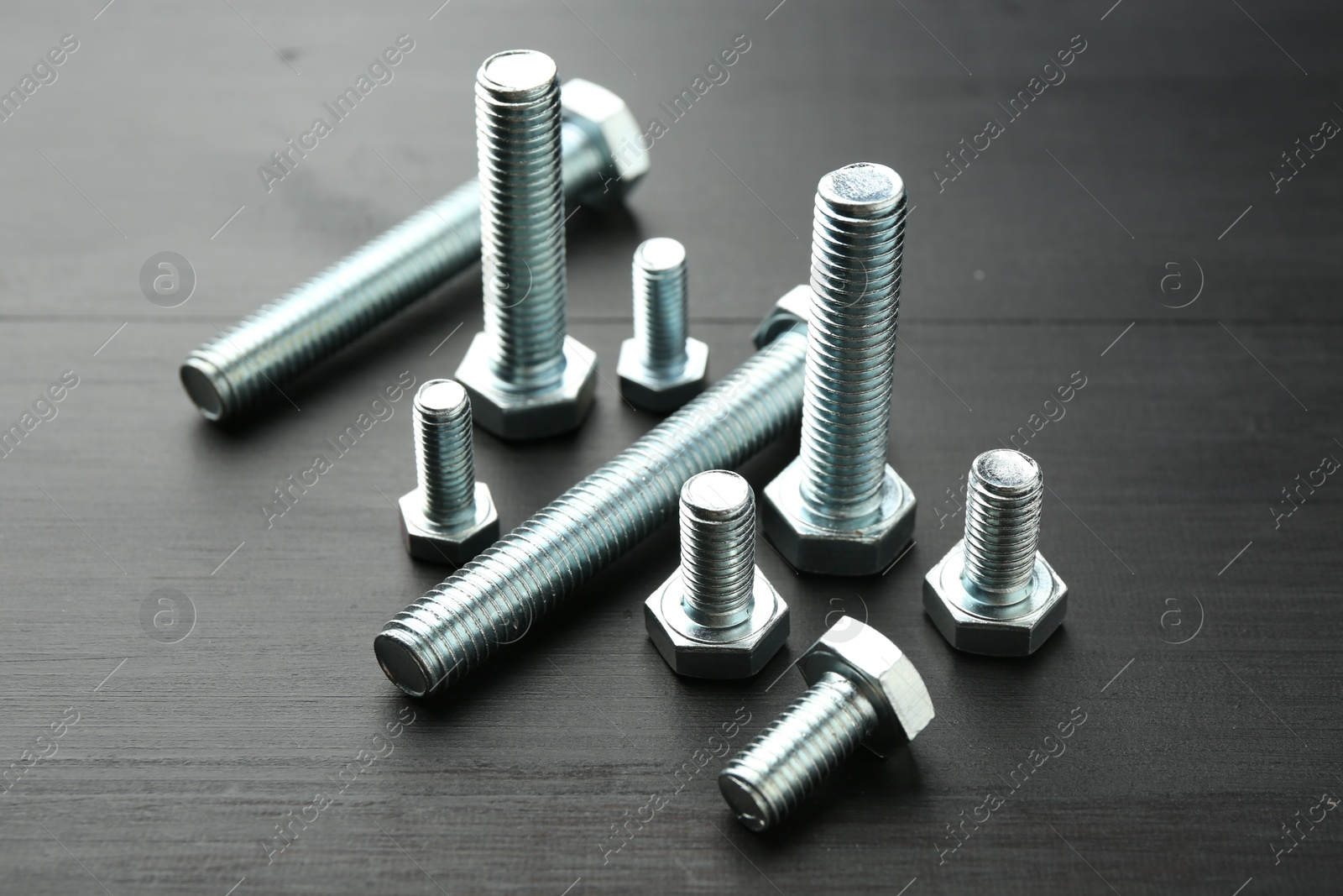 Metal bolts on dark wooden table, closeup Photo of Metal bolts on dark wooden table, closeup