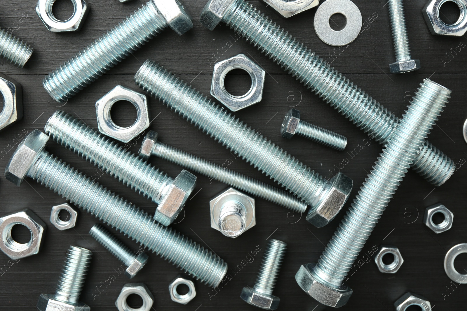 Set of metal bolts and hex nuts on black wooden table, flat lay Photo of Set of metal bolts and hex nuts on black wooden table, flat lay