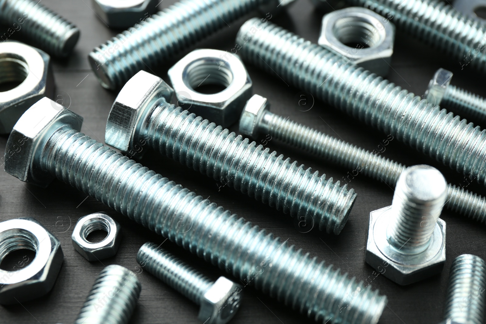 Metal bolts and hex nuts on dark wooden table, closeup Photo of Metal bolts and hex nuts on dark wooden table, closeup