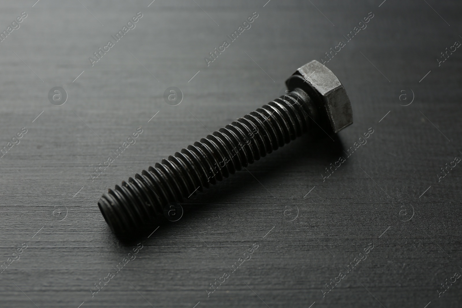 One metal bolt on dark wooden table, closeup Photo of One metal bolt on dark wooden table, closeup