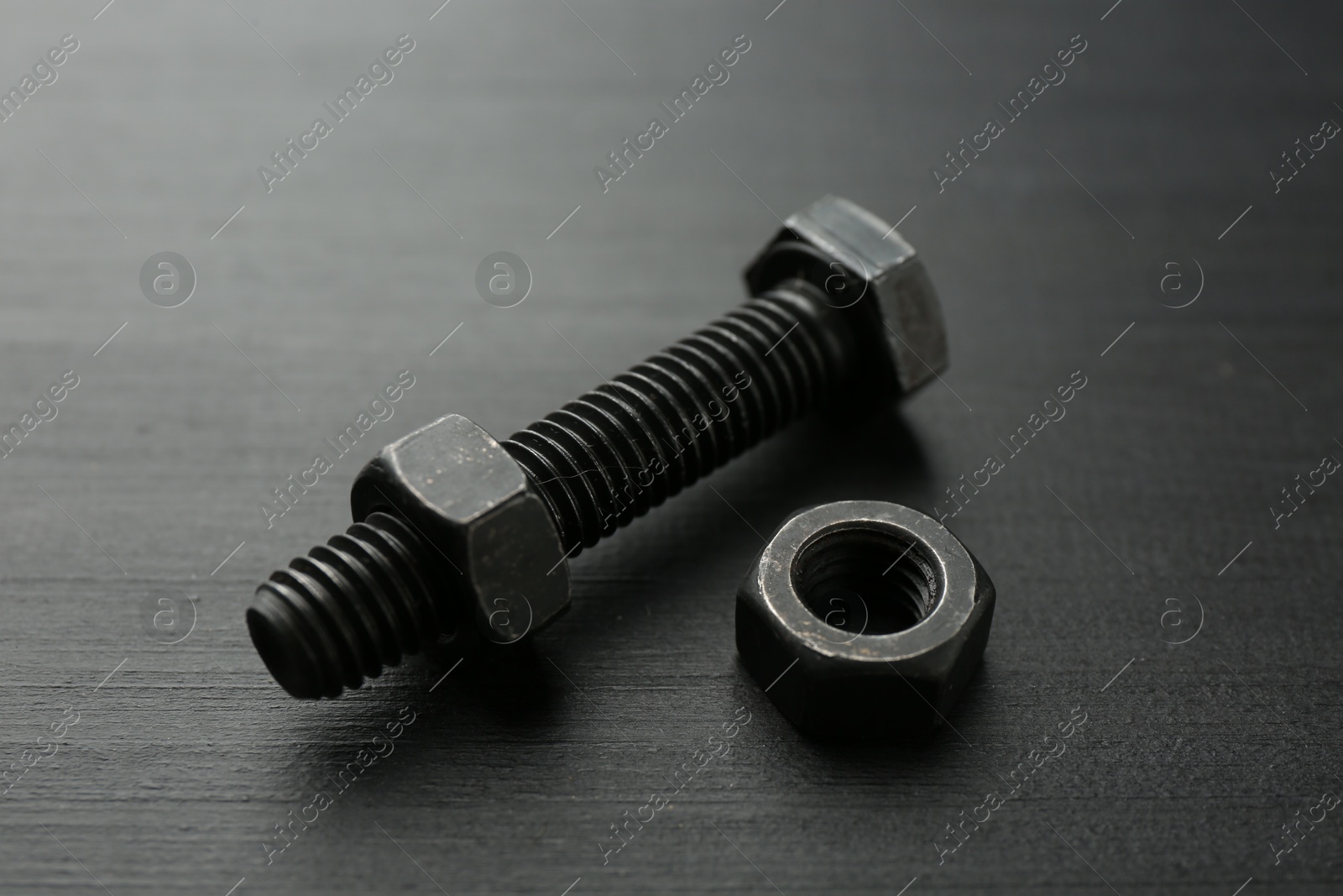 One metal bolt and hex nut on dark wooden table, closeup Photo of One metal bolt and hex nut on dark wooden table, closeup