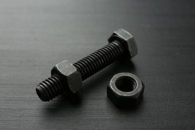 Photo of One metal bolt and hex nut on dark wooden table, closeup