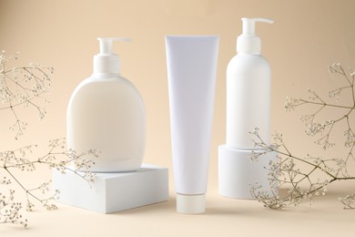 Photo of Promotion. Cosmetic products, podiums and gypsophila flowers on beige background