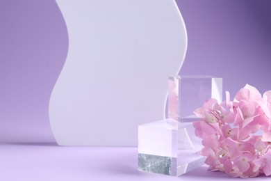 Photo of Promotion. Glass podium for product presentation and hydrangea flowers on violet background, closeup
