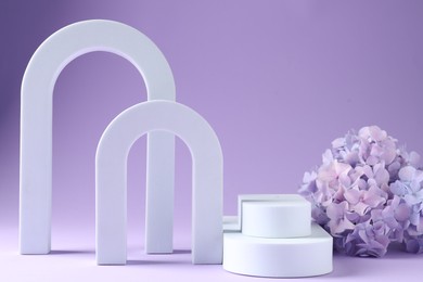 Photo of Promotion. Different podiums for product presentation and hydrangea flowers on violet background