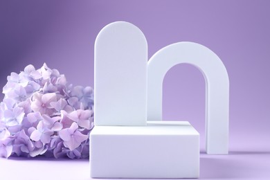 Photo of Promotion. Different podiums for product presentation and hydrangea flowers on violet background, closeup