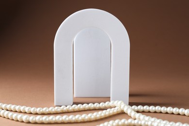 Photo of Promotion. White figures and pearl jewelry on brown background, closeup