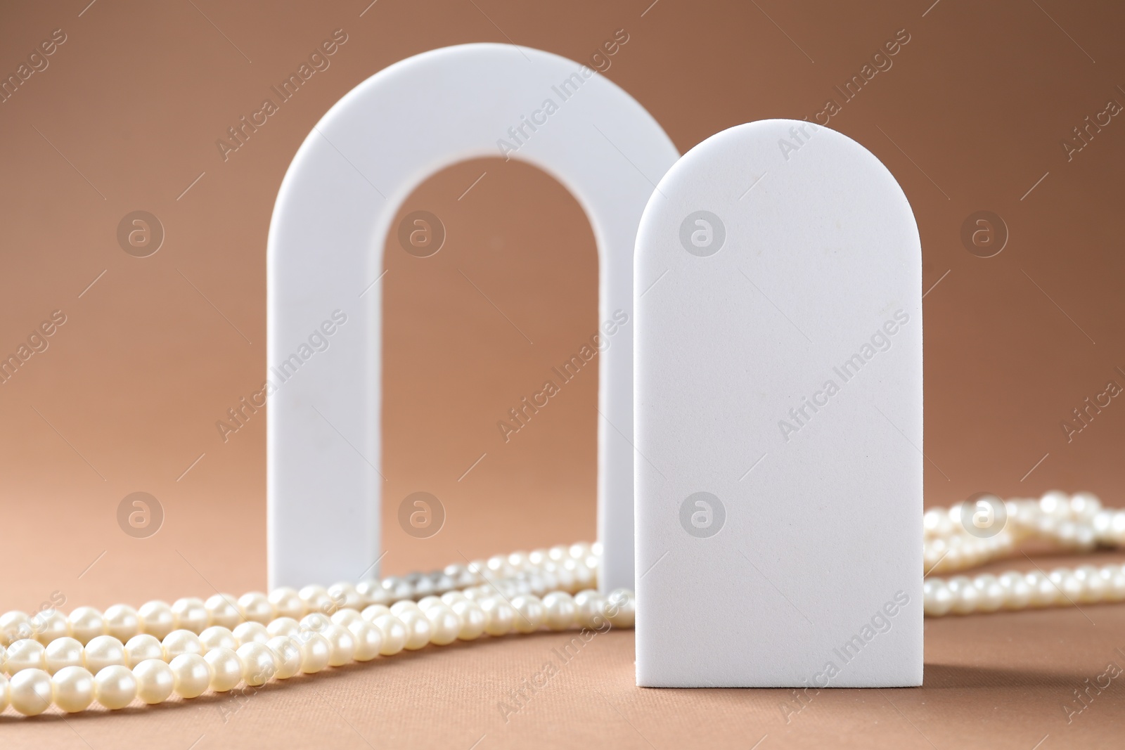 Promotion. White figures and pearl jewelry on brown background, closeup Photo of Promotion. White figures and pearl jewelry on brown background, closeup