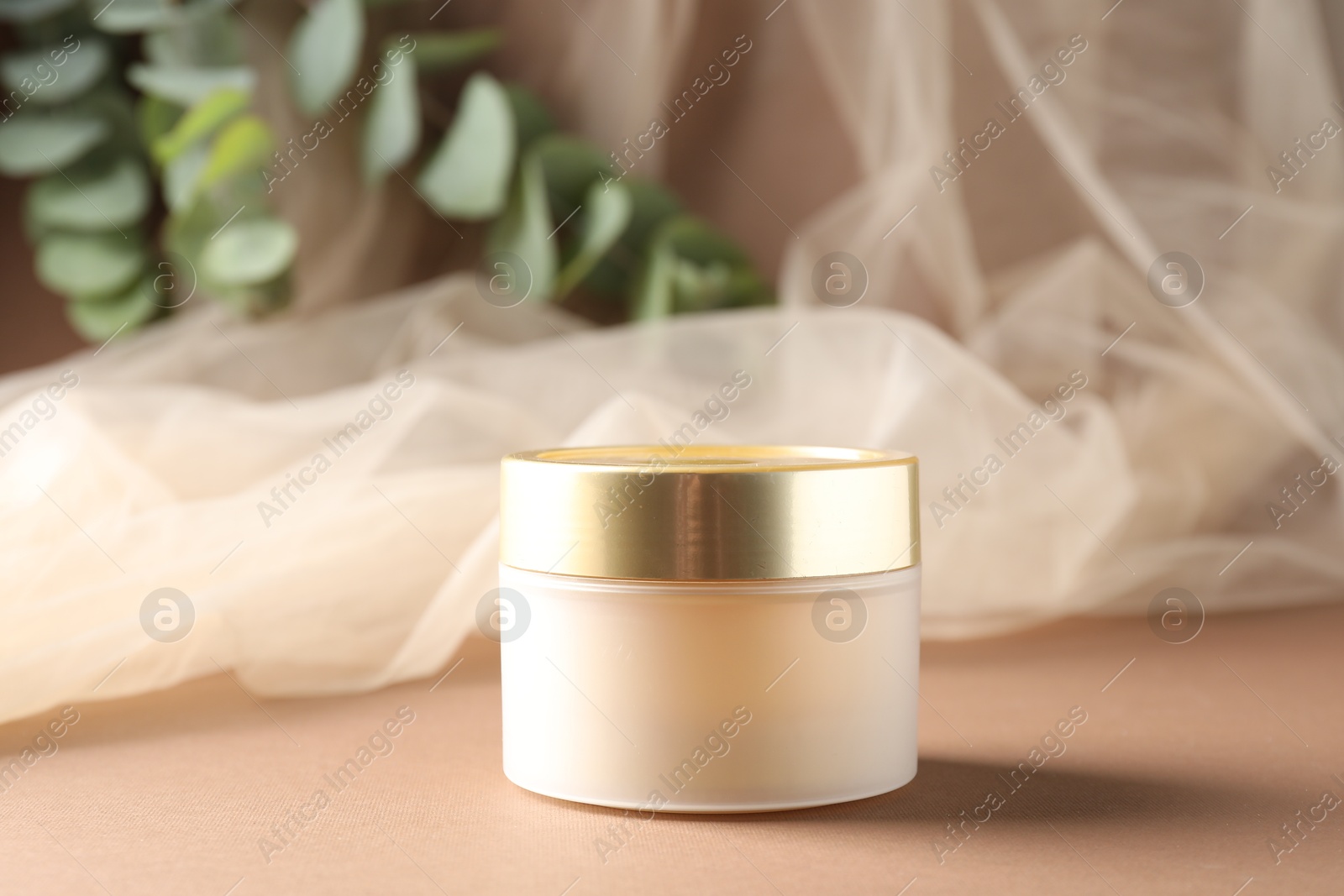 Promotion. Jar of cosmetic product, tulle cloth and green leaves on brown background, closeup Photo of Promotion. Jar of cosmetic product, tulle cloth and green leaves on brown background, closeup