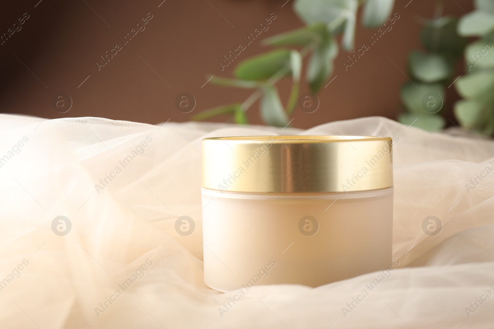 Promotion. Jar of cosmetic product, tulle cloth and green leaves on brown background, closeup Photo of Promotion. Jar of cosmetic product, tulle cloth and green leaves on brown background, closeup
