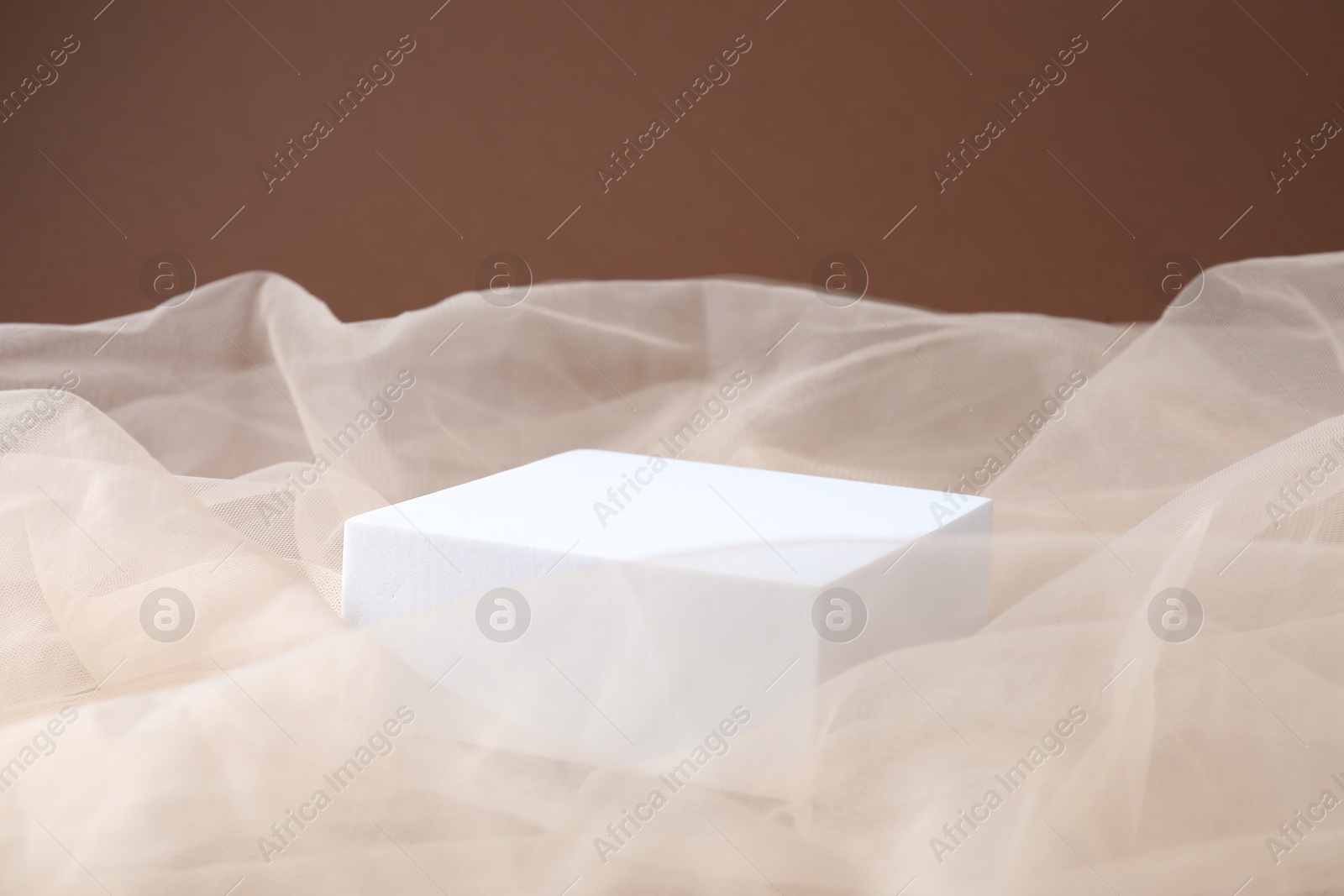 Promotion. Podium for product presentation and tulle cloth on brown background, closeup Photo of Promotion. Podium for product presentation and tulle cloth on brown background, closeup