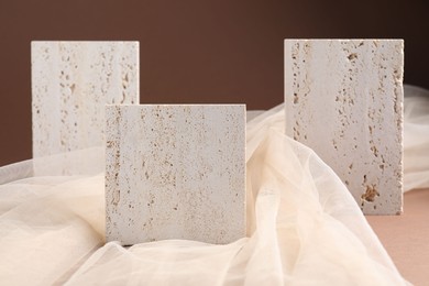 Photo of Promotion. Podiums for product presentation and tulle cloth on brown background, closeup