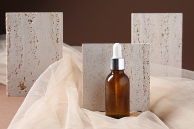 Photo of Promotion. Bottle of cosmetic product and tulle cloth on brown background, closeup