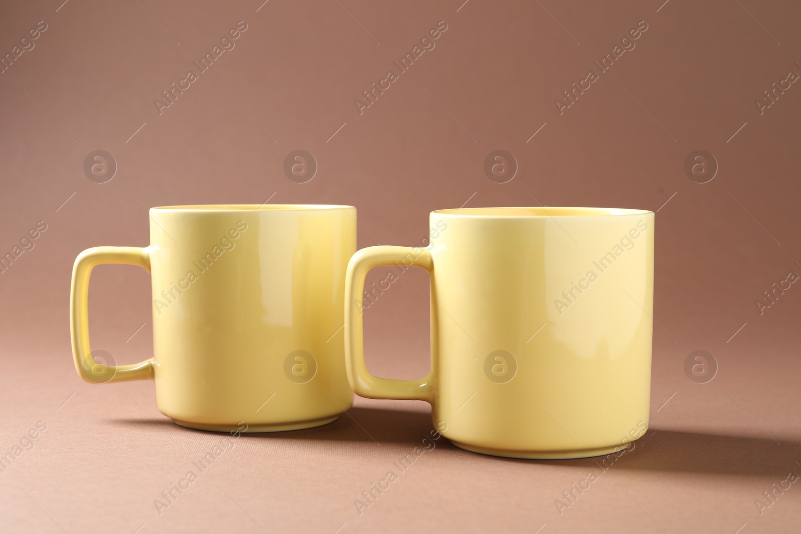 Promotion. Two yellow mugs on brown background Photo of Promotion. Two yellow mugs on brown background
