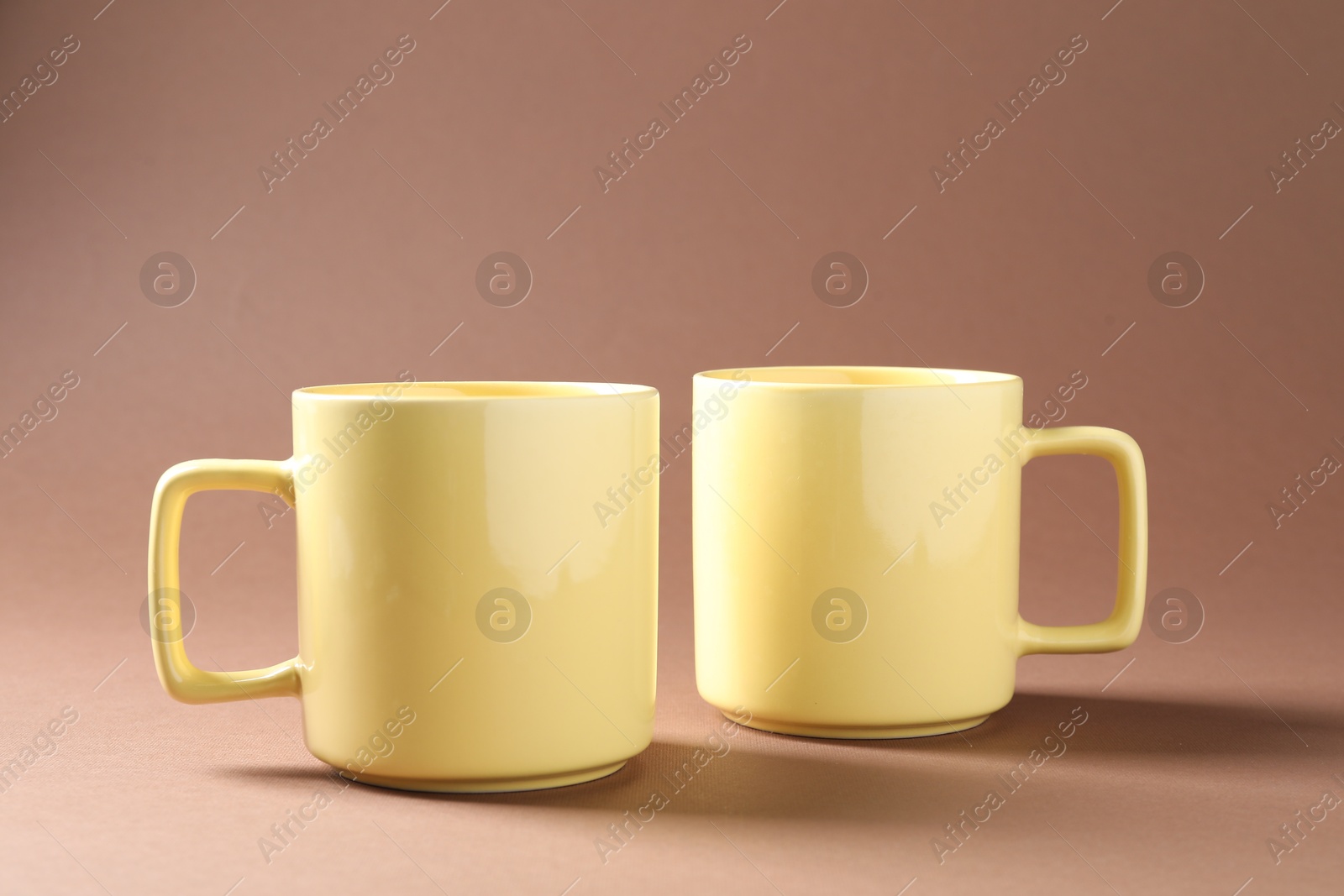 Promotion. Two yellow mugs on brown background Photo of Promotion. Two yellow mugs on brown background