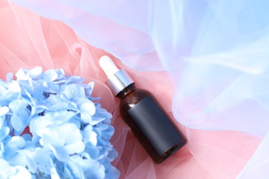 Photo of Promotion. Bottle of cosmetic product and hydrangea flowers on tulle cloth, top view