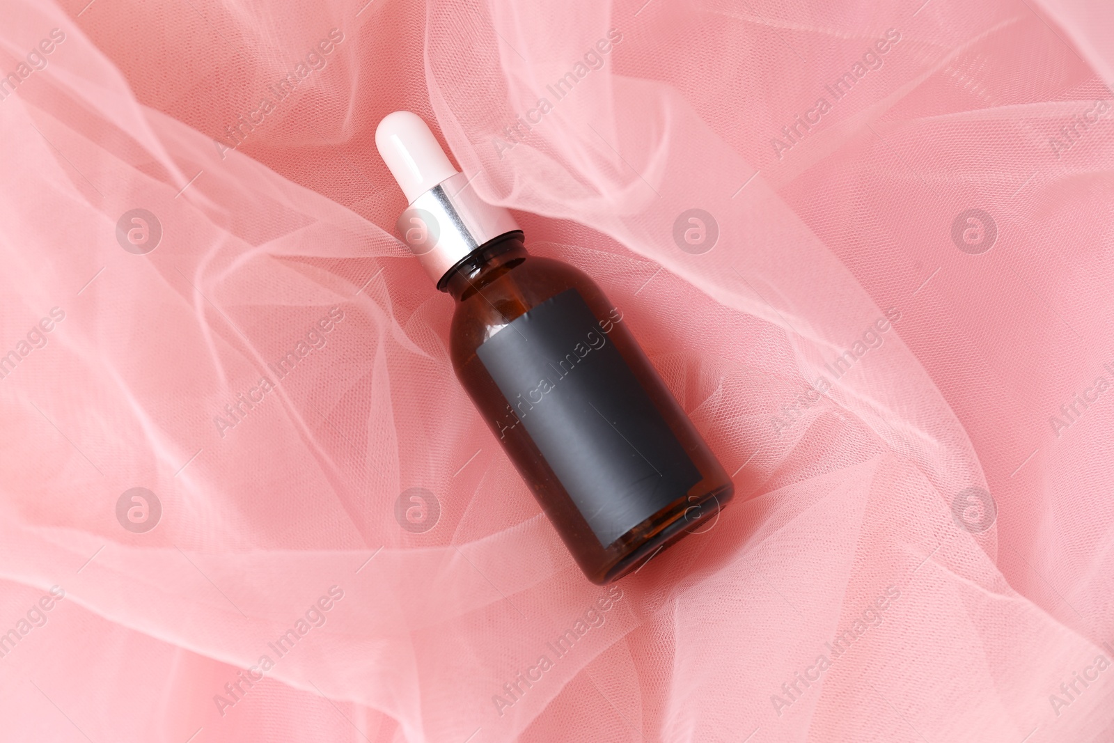 Promotion. Bottle of cosmetic product on tulle cloth, top view Photo of Promotion. Bottle of cosmetic product on tulle cloth, top view
